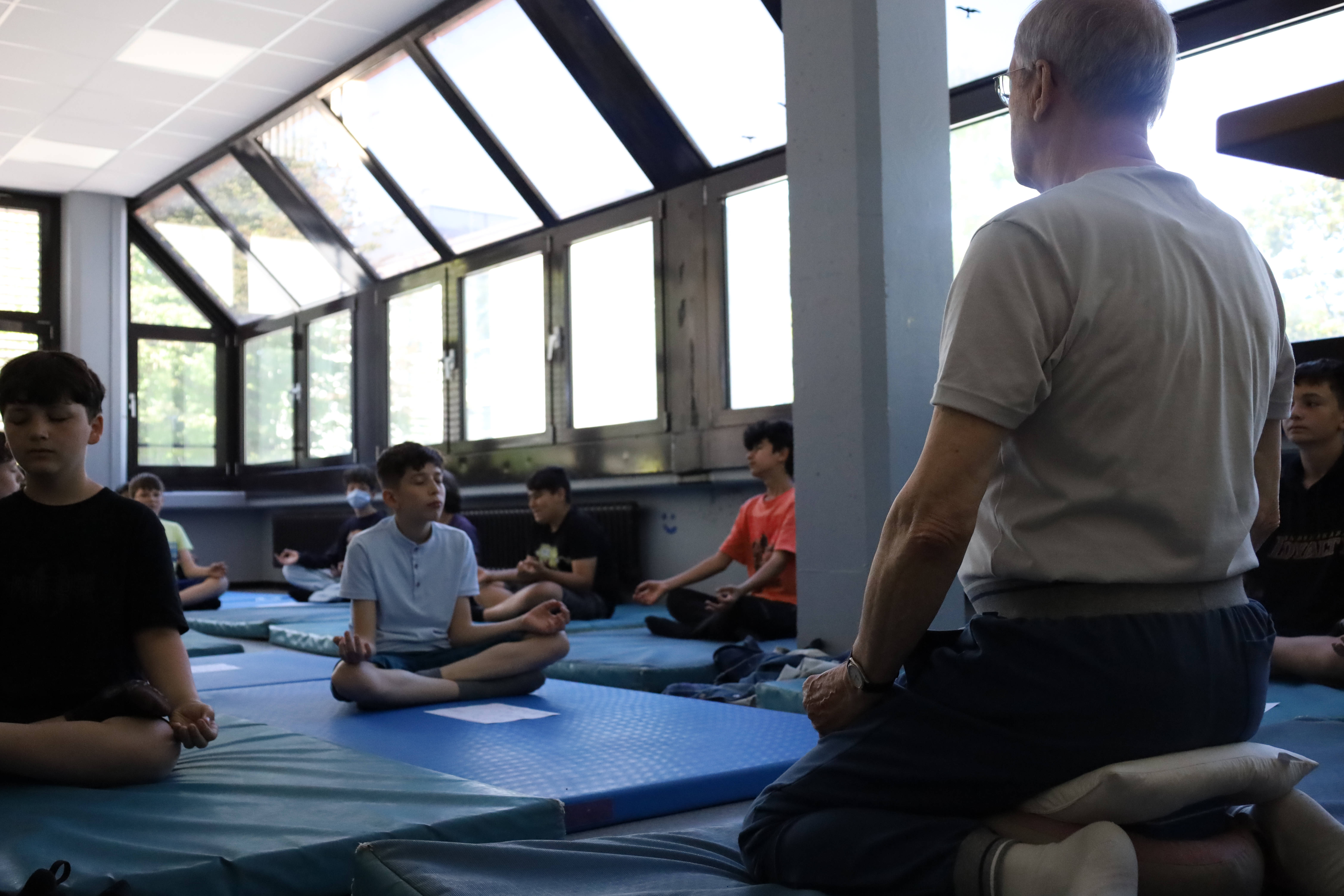 Schüler der Klassen 6 führen auf Yogamatten die Übungen nach Anweisungen ihres Yogalehrers aus. 
